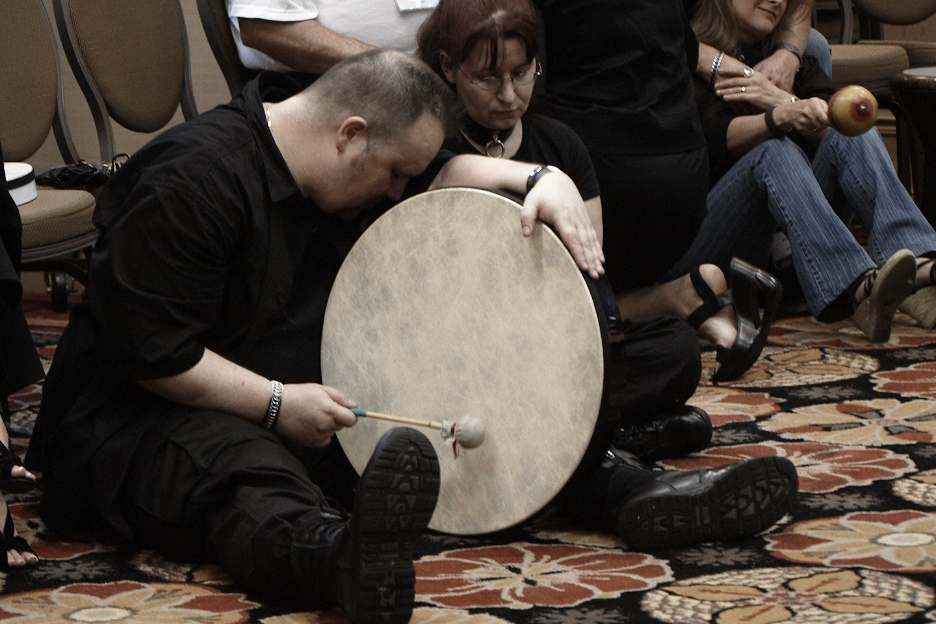 People gathered in a circle drumming together
